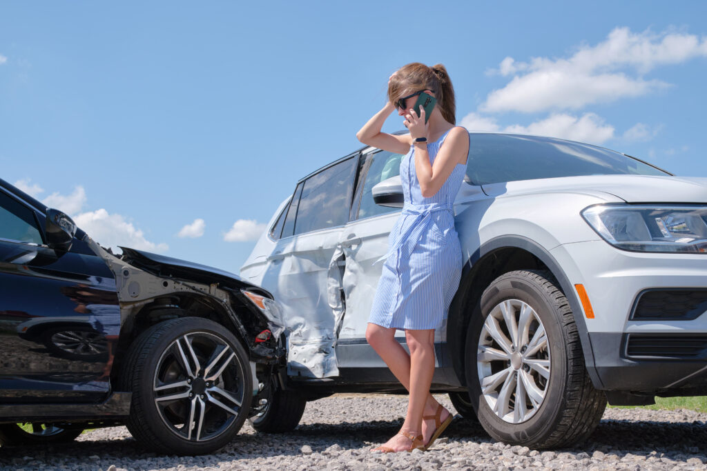 How to document a car accident. Sad female driver speaking on sellphone on street side calling for emergency service after car accident. Road safety and insurance concept.